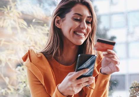 Woman holding phone and credit card.
