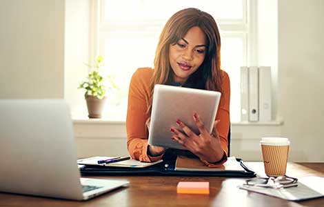 Business woman at desk using tablet.