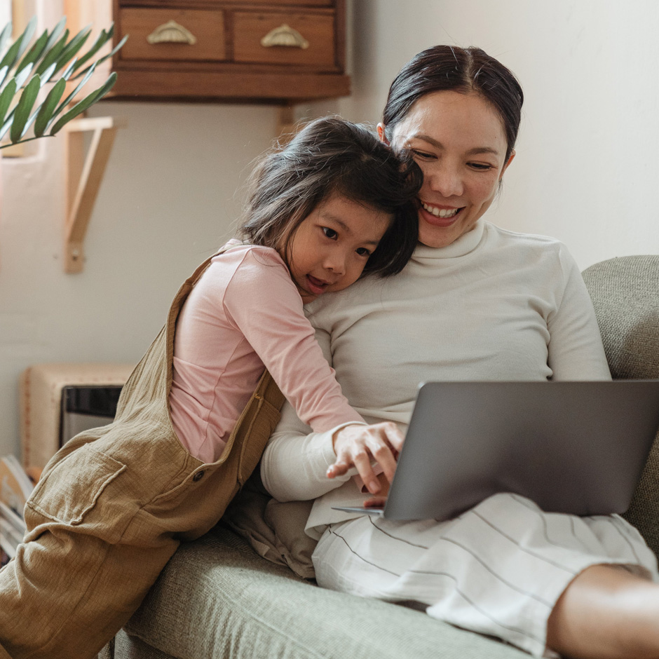 Woman working on her computer with her daughter watching on