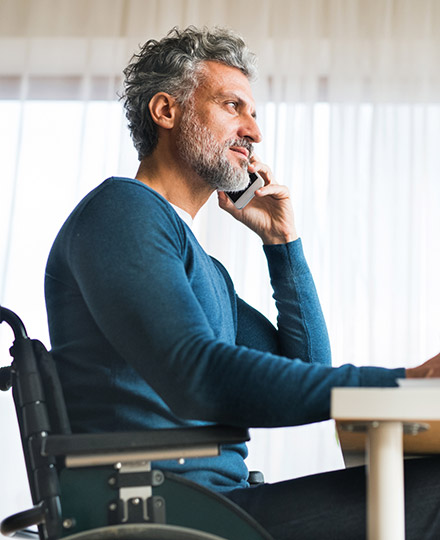 Man in wheelchair using cell phone.