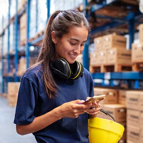 Woman looking at phone in warehouse.
