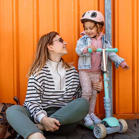 Woman looking at child on scooter.