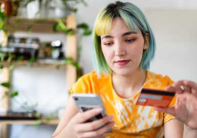 Girl holding credit card and phone at home.