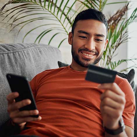 Man looking at card and phone from couch.