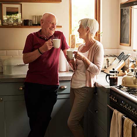 Mature couple drinking coffee in kitchen.