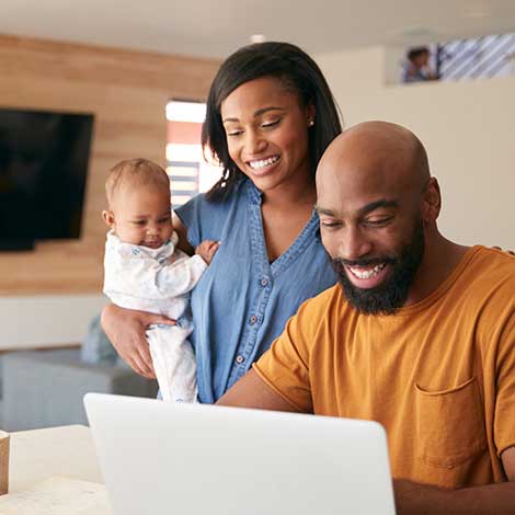 Couple and baby using laptop.